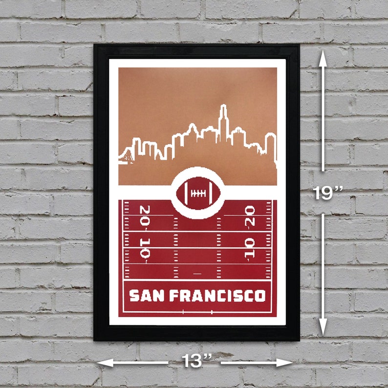 May include: A framed print with a red and brown color scheme. The print features a white silhouette of the San Francisco skyline with a football field and the text "SAN FRANCISCO" below. The print measures 13 inches wide by 19 inches tall.