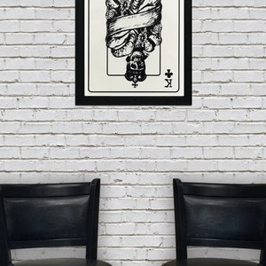 May include: A black and white illustration of the King of Clubs playing card. The king is depicted as a skeleton wearing a crown and is wrapped in a scroll. The card is framed in black.