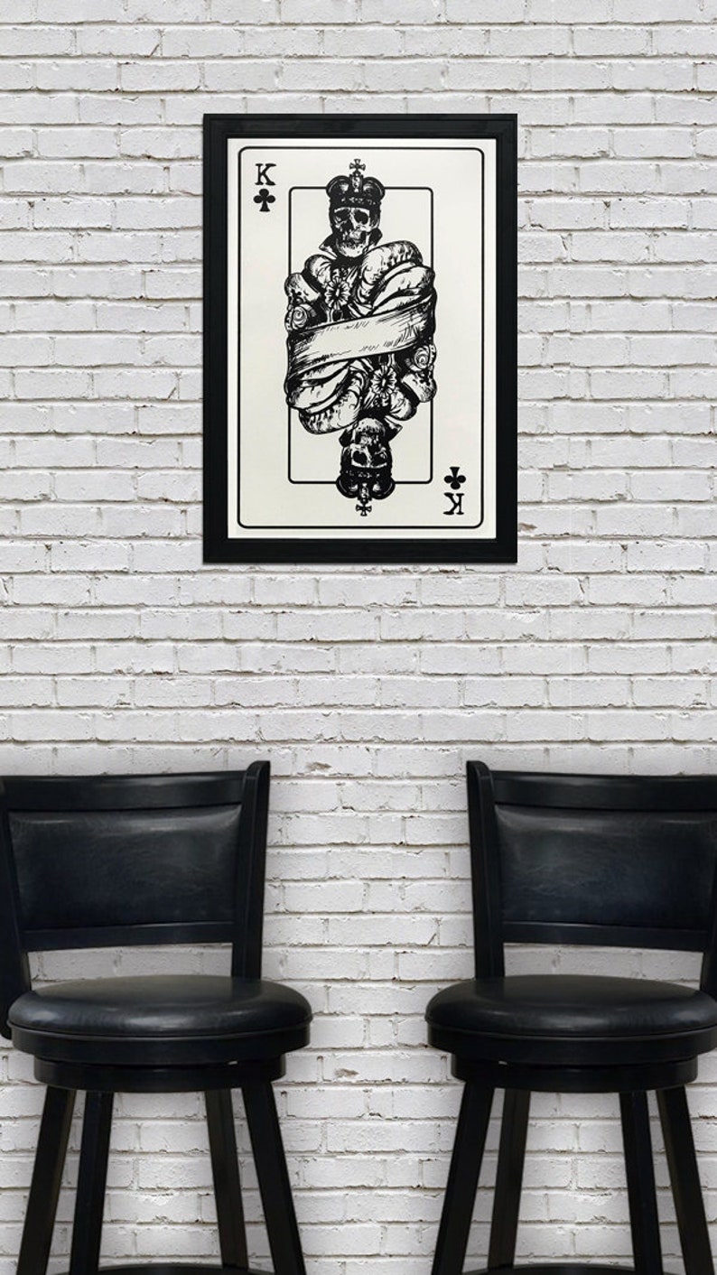 May include: A black and white illustration of the King of Clubs playing card. The king is depicted as a skeleton wearing a crown and is wrapped in a scroll. The card is framed in black.