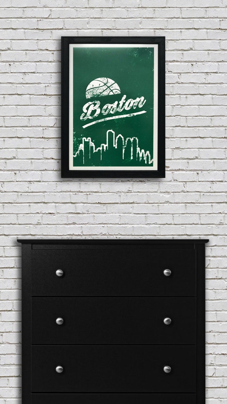 May include: A framed print with a green background and white text that says "Boston". A basketball is above the text and a white silhouette of the Boston skyline is below the text.