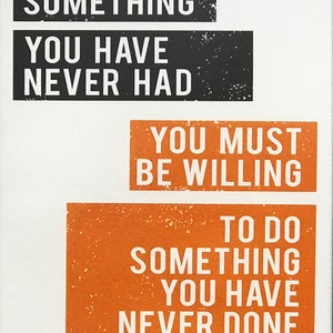 May include: A motivational quote printed on a white background with black and orange text. The quote reads: "You must be willing to do something you have never done."