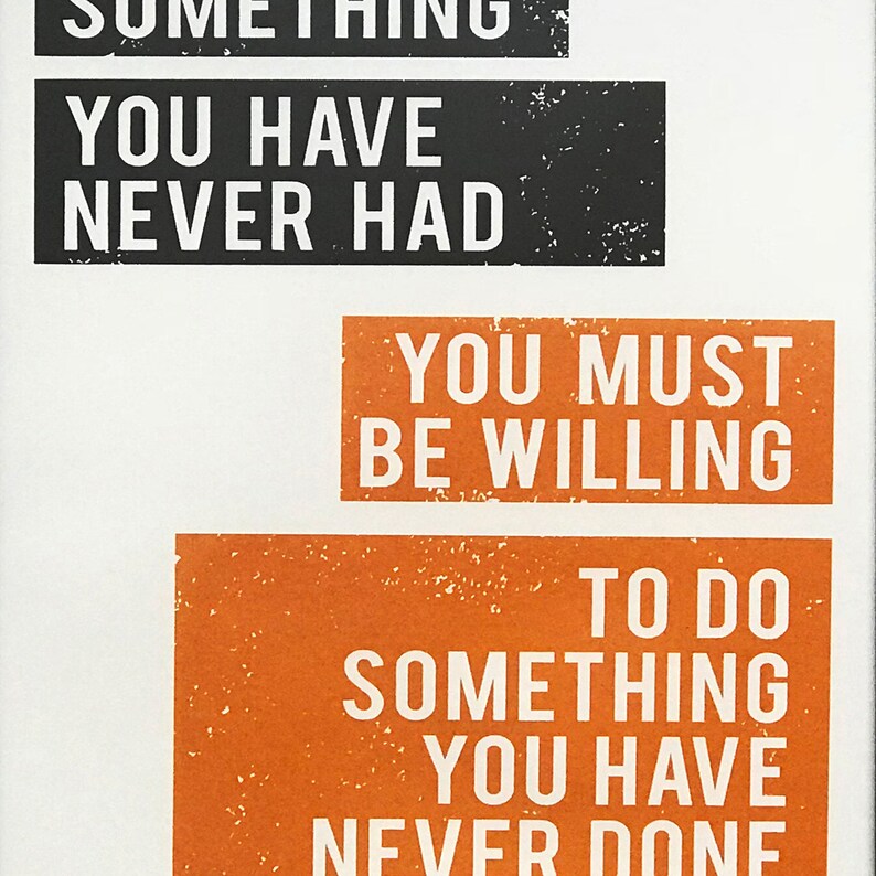 May include: A motivational quote printed on a white background with black and orange text. The quote reads: "You must be willing to do something you have never done."