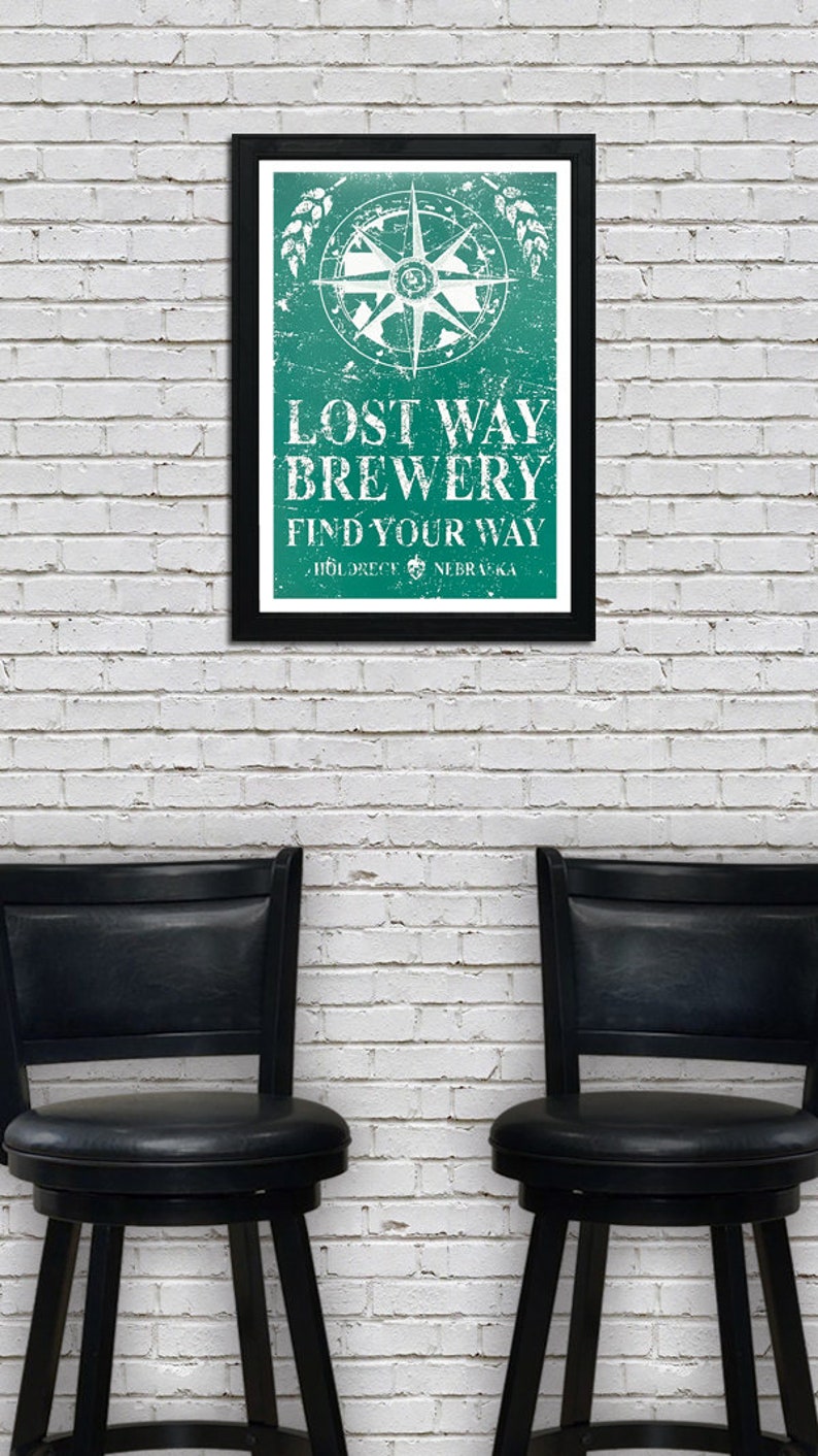 May include: A framed poster with a distressed green background and a white compass design. The text reads "Lost Way Brewery Find Your Way" with the location "Holdrege, Nebraska" below.