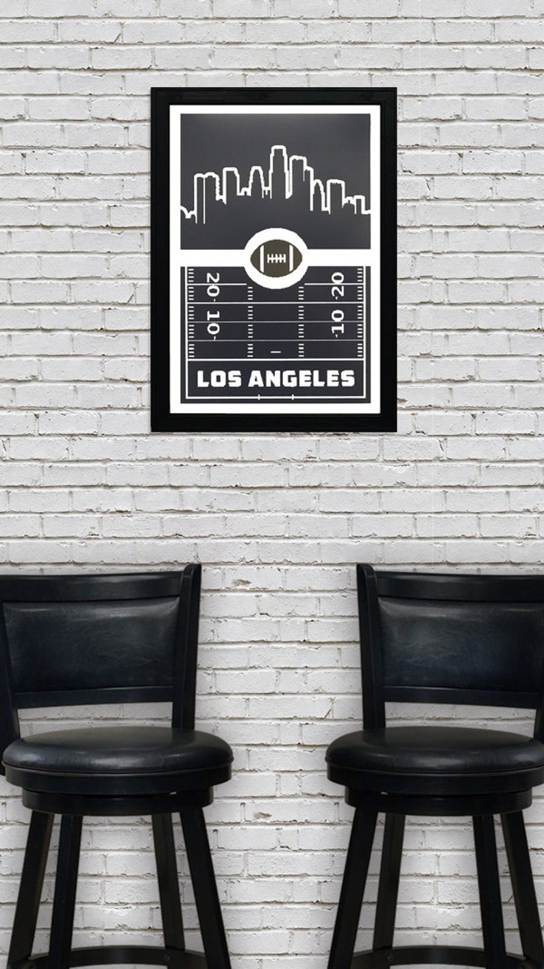 May include: Black and white framed print of a football field with a skyline of Los Angeles, California. The text "LOS ANGELES" is printed below the field.