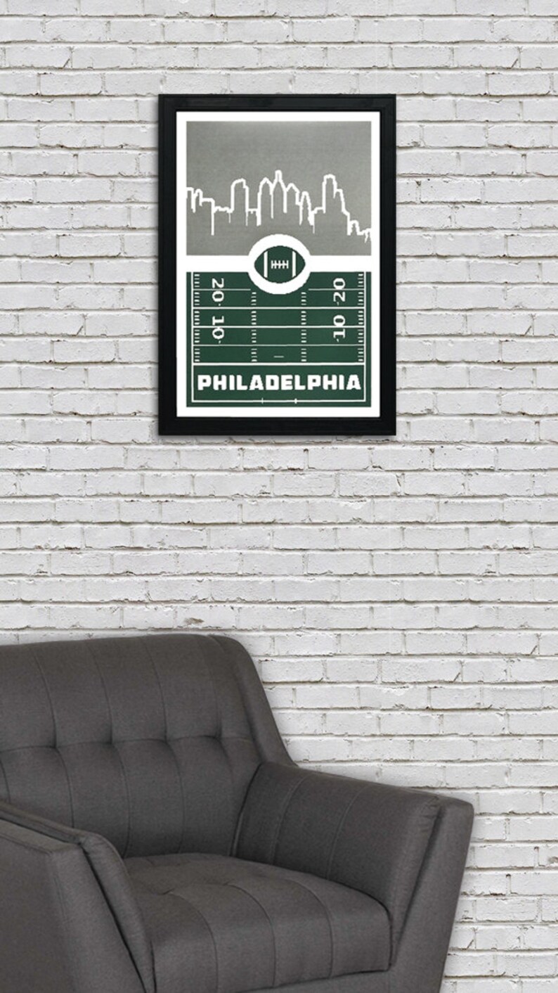 May include: A framed print of a green football field with a white outline of the Philadelphia skyline above it. The text "PHILADELPHIA" is printed below the field.
