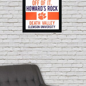 May include: A black framed poster with the text "Give me 110% or keep your filthy hands off of it. Howard's Rock. Death Valley. Clemson University." The poster has an orange and purple paw print.