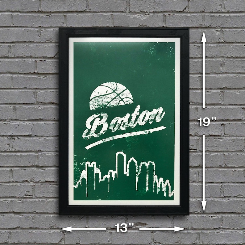 May include: A green and white poster with a basketball and the word "Boston" in a white distressed font. The poster also features a white silhouette of the Boston skyline. The poster is framed in black and measures 13 inches by 19 inches.