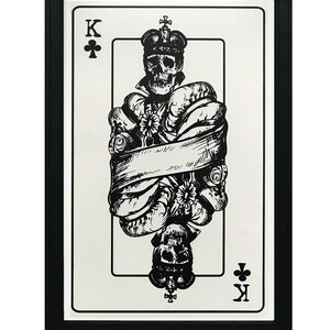 May include: A black and white illustration of the King of Clubs playing card. The card features a skull wearing a crown and surrounded by tentacles. The card is framed in black.