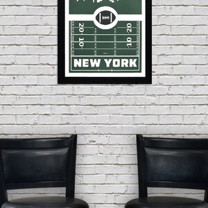 Puede incluir: Una impresi&oacute;n enmarcada con un fondo verde que presenta una silueta blanca del horizonte de la ciudad de Nueva York. El horizonte est&aacute; sobre un campo de f&uacute;tbol con l&iacute;neas de yarda y las palabras "NUEVA YORK" debajo del campo.