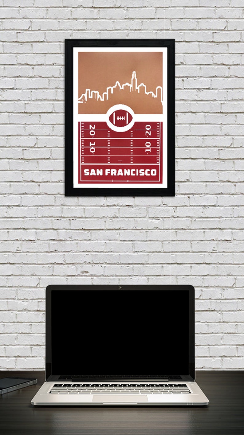 May include: A framed print of a red and white football field with a white outline of the San Francisco skyline above it. The text "SAN FRANCISCO" is printed below the field.