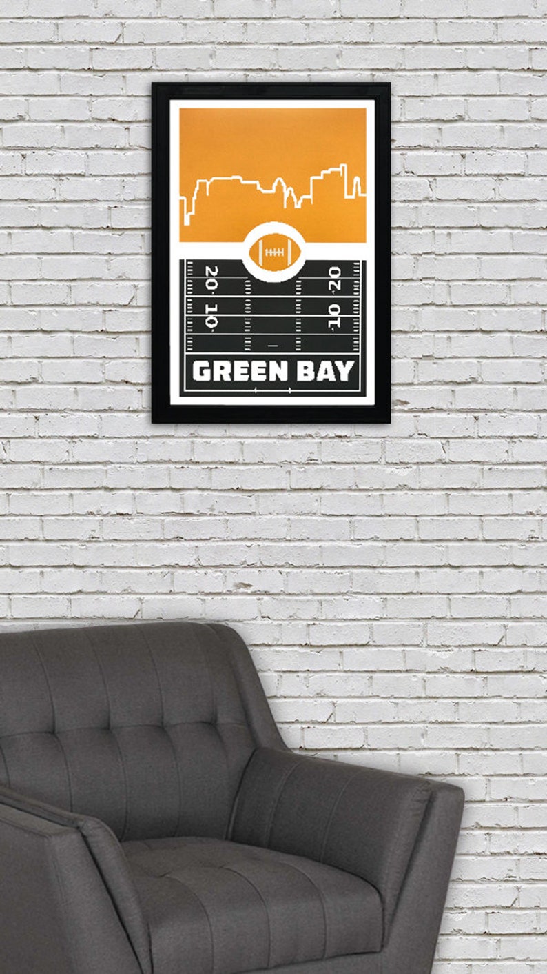 May include: A black and white framed print with a yellow cityscape and a football field. The text "GREEN BAY" is printed below the field.