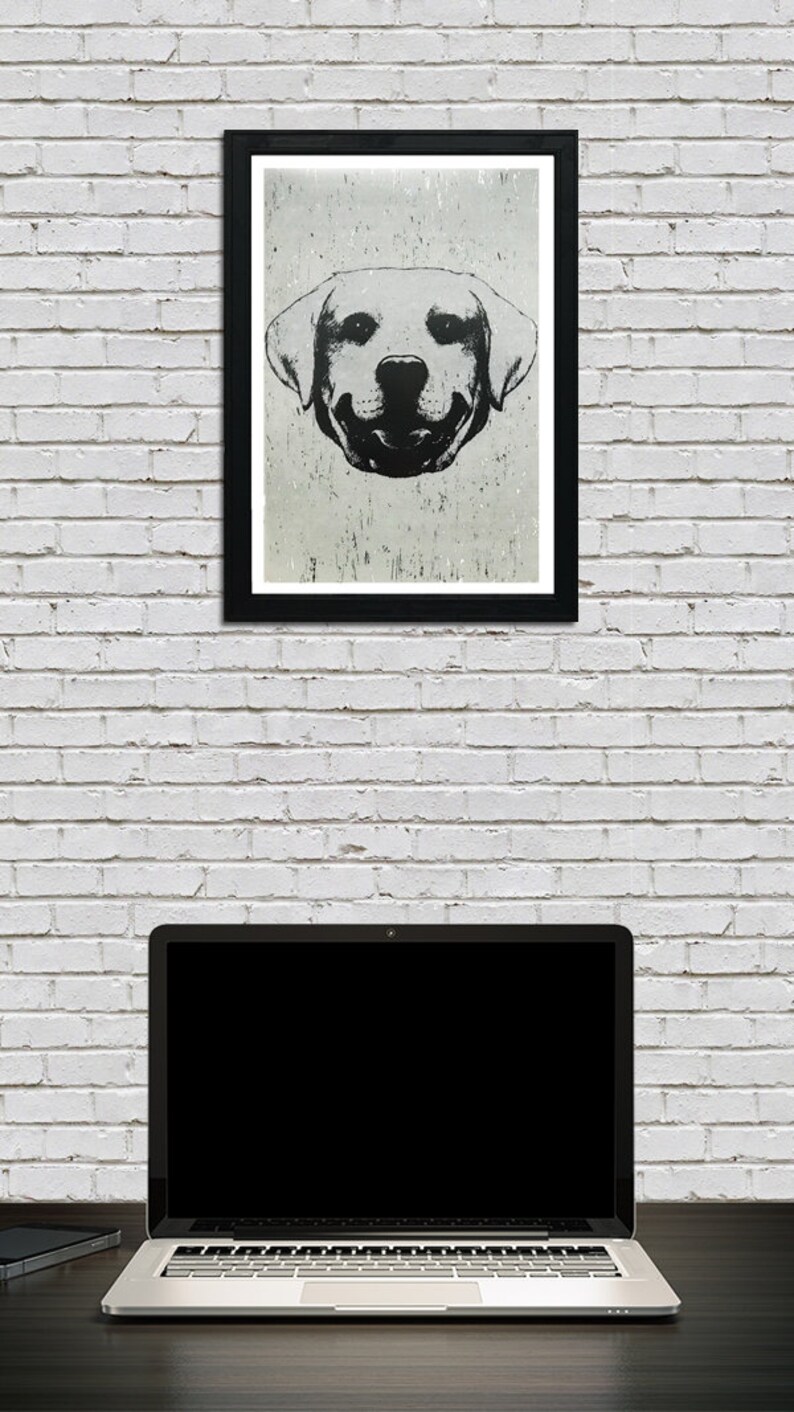 Puede incluir: Ilustraci&oacute;n en blanco y negro de la cara de un perro con fondo blanco. El perro est&aacute; sonriendo con la lengua fuera. La ilustraci&oacute;n est&aacute; enmarcada en un marco negro y colgada en una pared de ladrillo blanco.