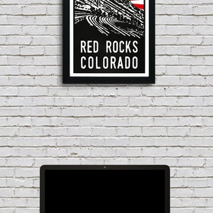 May include: Black and white illustration of Red Rocks Amphitheatre in Colorado with a red and white sunburst behind it. The text "Red Rocks Colorado" is below the illustration.