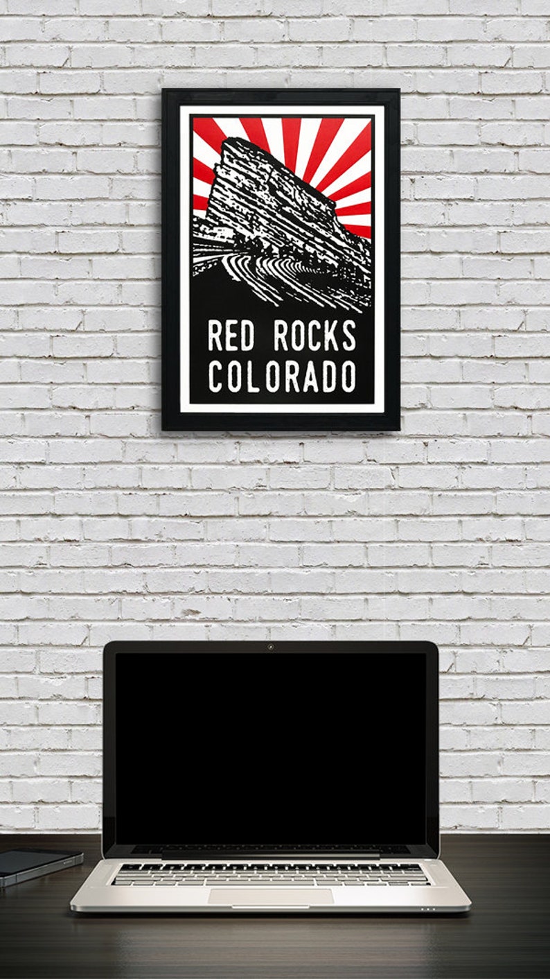 May include: Black and white illustration of Red Rocks Amphitheatre in Colorado with a red and white sunburst behind it. The text "Red Rocks Colorado" is below the illustration.