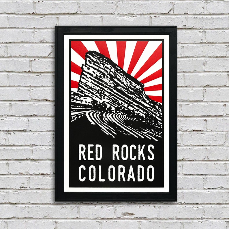 May include: A black and white illustration of Red Rocks Amphitheatre in Colorado with a red and white sunburst behind it. The text "Red Rocks Colorado" is printed below the illustration.