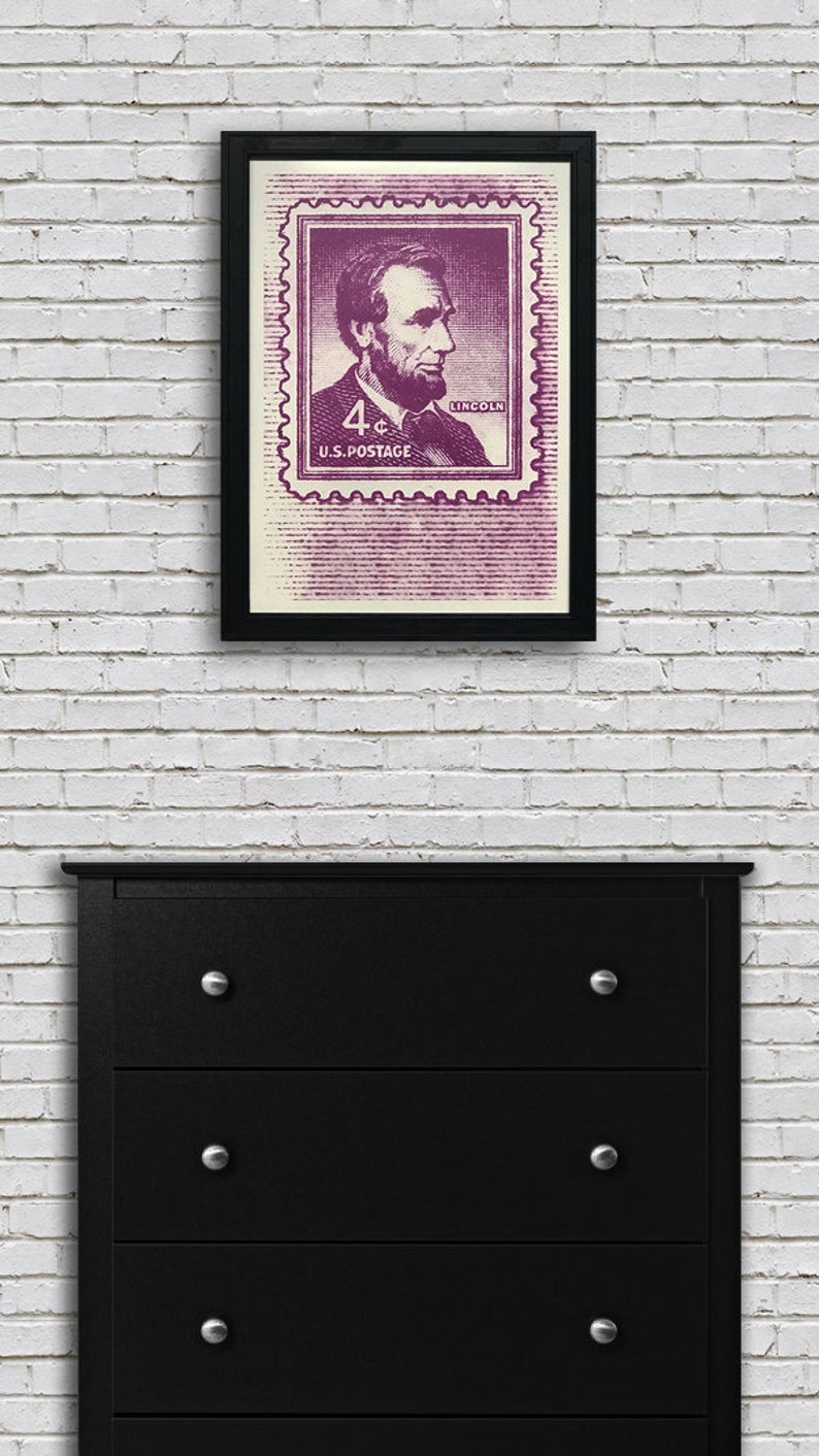 May include: A framed print of a vintage US postage stamp featuring a portrait of Abraham Lincoln. The stamp is purple and reads "4&cent; U.S. POSTAGE" and "LINCOLN".