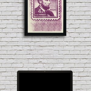 May include: A framed print of a vintage 4&cent; US postage stamp featuring a portrait of Abraham Lincoln. The stamp is in shades of purple and white with the text "4&cent; U.S. POSTAGE" and "LINCOLN".