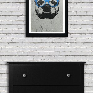 May include: A black and white illustration of a bulldog wearing blue glasses. The image is printed on a textured paper and framed in a black frame.