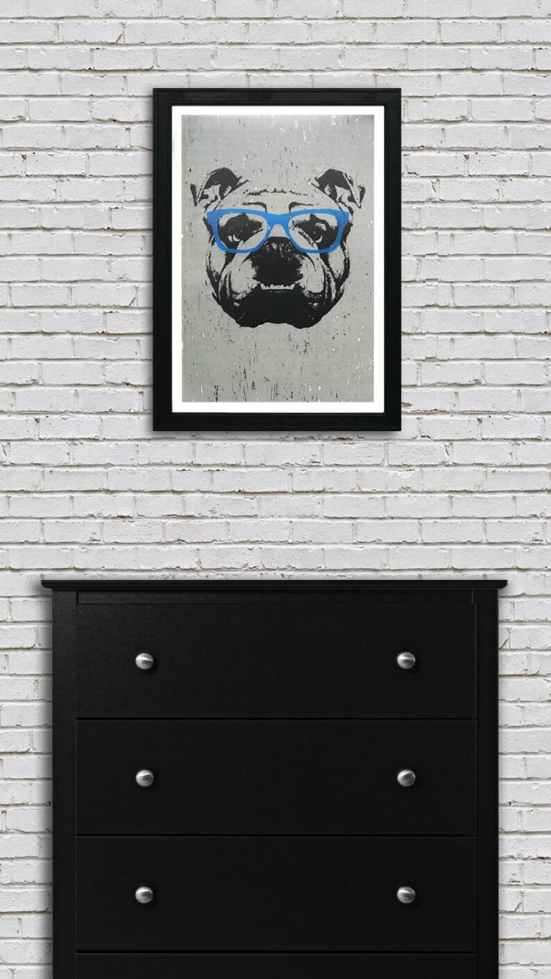 May include: A black and white illustration of a bulldog wearing blue glasses. The image is printed on a textured paper and framed in a black frame.