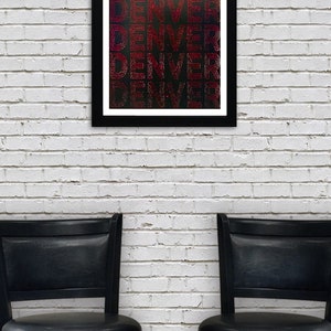 May include: A framed print with the word "DENVER" repeated in a red and white striped pattern on a black background. The print is hanging on a white brick wall above two black bar stools.