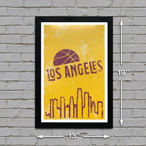 May include: Framed poster with a yellow background featuring a basketball and the text "LOS ANGELES" in a distressed font. The poster also includes a skyline silhouette. The framed poster measures 19 inches high and 13 inches wide.