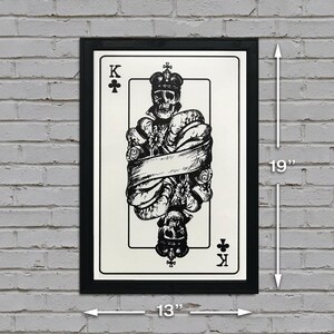 May include: Black and white illustration of the King of Clubs playing card featuring a skull wearing a crown and surrounded by flowers and a banner. The card is framed in a black frame and measures 13 inches wide by 19 inches tall.