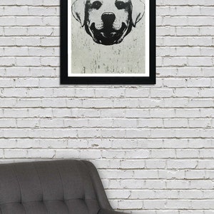 Puede incluir: Ilustraci&oacute;n en blanco y negro de la cara de un perro con una expresi&oacute;n sonriente. El perro es un labrador retriever con orejas ca&iacute;das. La ilustraci&oacute;n est&aacute; enmarcada en un marco negro y colgada en una pared de ladrillo blanco.