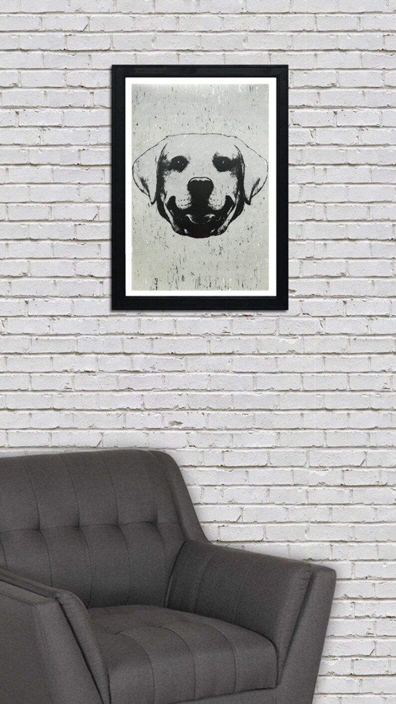 Puede incluir: Ilustraci&oacute;n en blanco y negro de la cara de un perro con una expresi&oacute;n sonriente. El perro es un labrador retriever con orejas ca&iacute;das. La ilustraci&oacute;n est&aacute; enmarcada en un marco negro y colgada en una pared de ladrillo blanco.