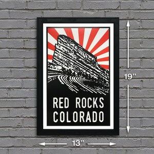 K&ouml;nnte beinhalten: Ein schwarz-wei&szlig;es Poster mit einem roten und wei&szlig;en Sonnenstrahlen-Design. Das Poster zeigt eine Schwarz-Wei&szlig;-Illustration des Red Rocks Amphitheaters in Colorado. Der Text "RED ROCKS COLORADO" ist in Wei&szlig; auf schwarzem Hintergrund gedruckt.