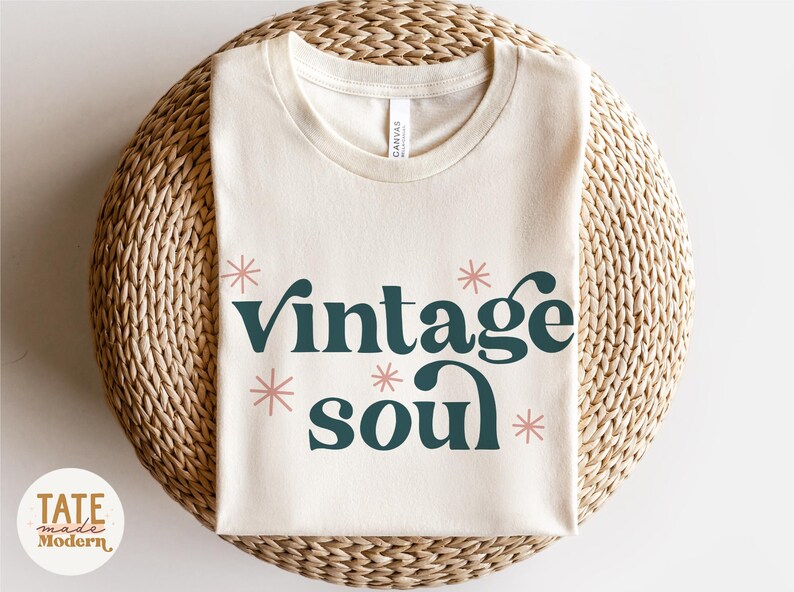 May include: A beige t-shirt with the text "vintage soul" in dark green letters with pink stars around the text.
