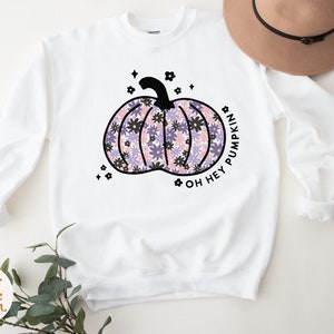 May include: White sweatshirt with a black floral pumpkin design and the text "Oh Hey Pumpkin".