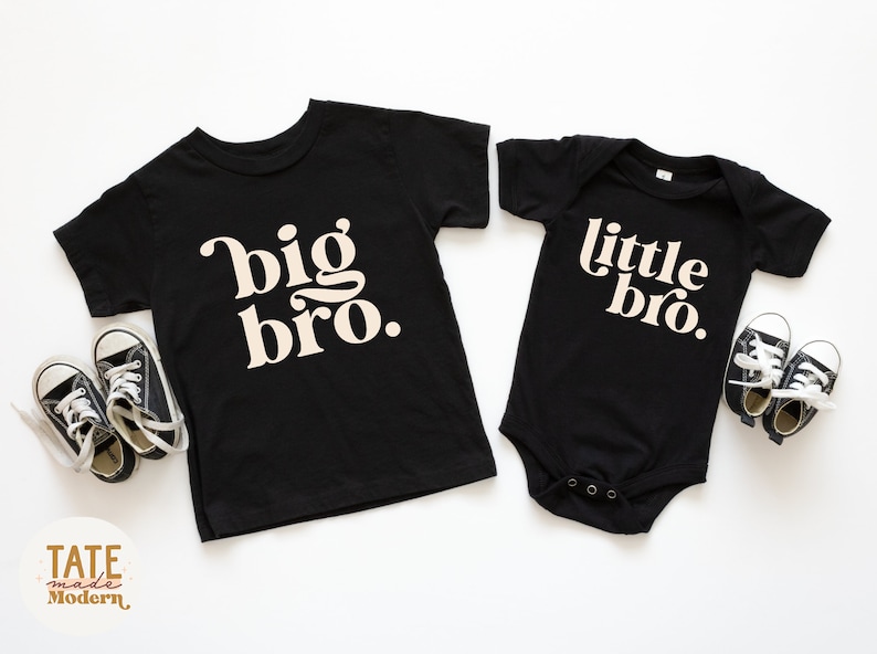 Puede incluir: Dos camisetas negras con texto blanco. La camiseta m&aacute;s grande dice "big bro." La camiseta m&aacute;s peque&ntilde;a dice "little bro."