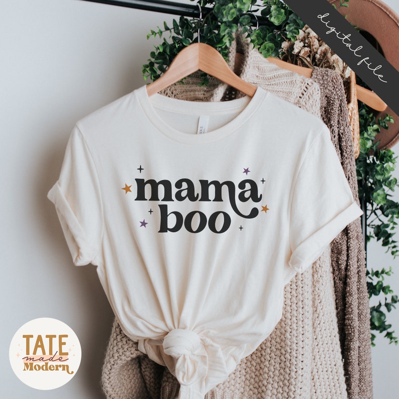 May include: A white t-shirt with the text "mama boo" in black with orange and purple stars.