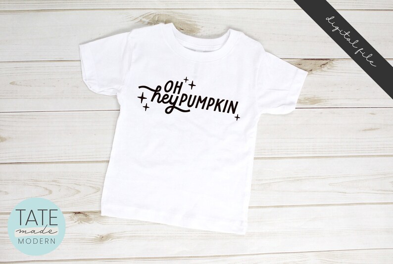 May include: White t-shirt with black text that reads "Oh hey pumpkin" with plus signs around the text.