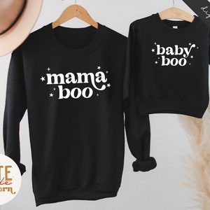 May include: Two black sweatshirts with white text. The larger sweatshirt says "mama boo" with stars around the text. The smaller sweatshirt says "baby boo" with stars around the text.