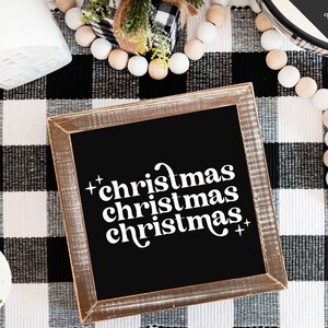 Pode incluir: Uma placa preta enquadrada com o texto "christmas christmas christmas" em branco sobre um fundo xadrez preto e branco.