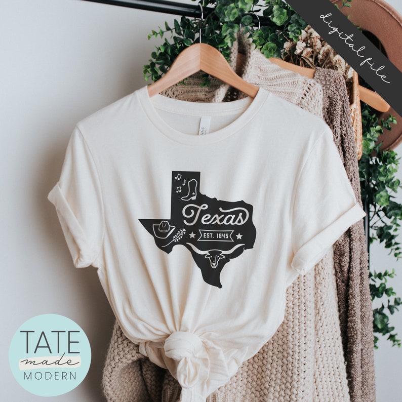 May include: A white t-shirt with a black outline of the state of Texas, with the word "Texas" and "Est. 1945" inside the outline. There are also images of a cowboy hat, boots, and a longhorn steer inside the outline.