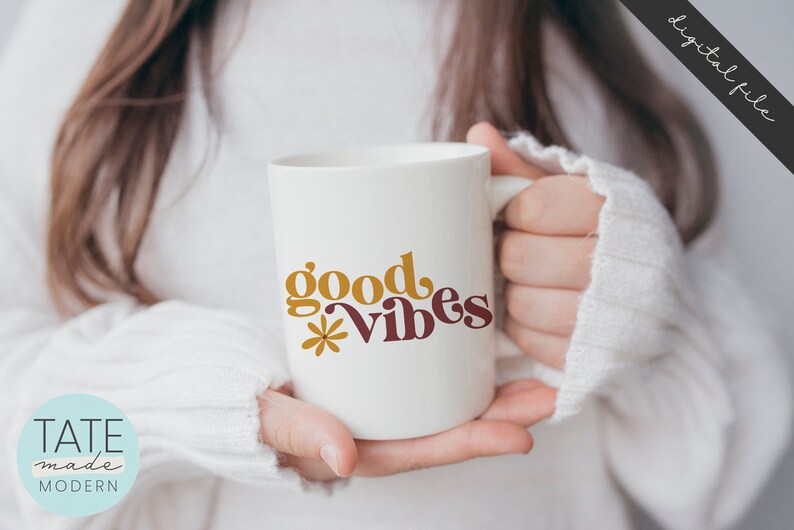 May include: White ceramic mug with the text "good vibes" in yellow and maroon lettering with a small flower graphic.