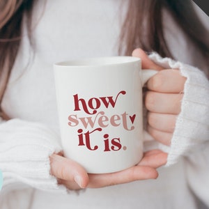 May include: White ceramic mug with the text "how sweet it is." in red and pink lettering. A small heart is included in the text.