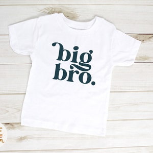 Puede incluir: Camiseta blanca con el texto "big bro." en fuente azul oscuro.