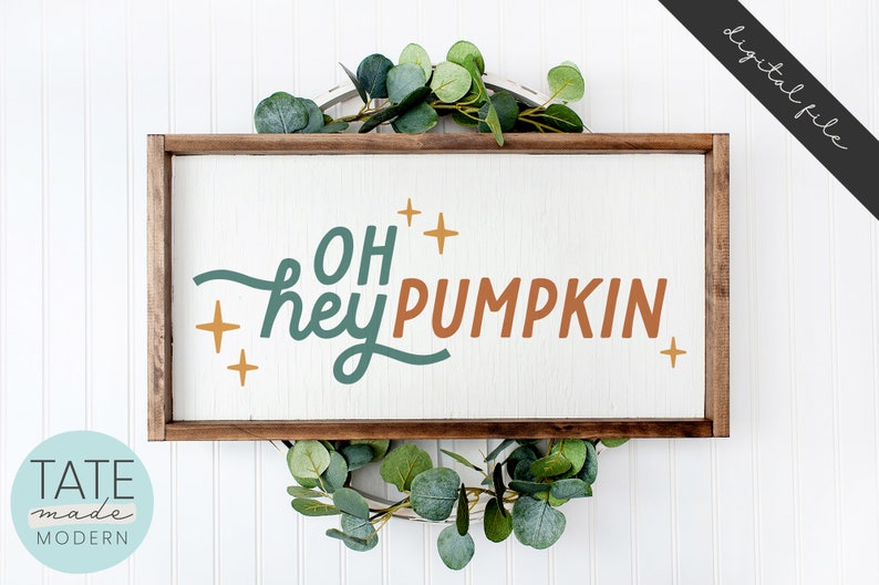 May include: A wooden sign with the text "Oh hey pumpkin" in teal and orange lettering with gold stars. The sign is framed in a brown wood frame and is sitting on a white background.