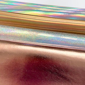 Op de afbeelding: Drie vellen iriserende holografische vinyl in goud, zilver en roze goud.