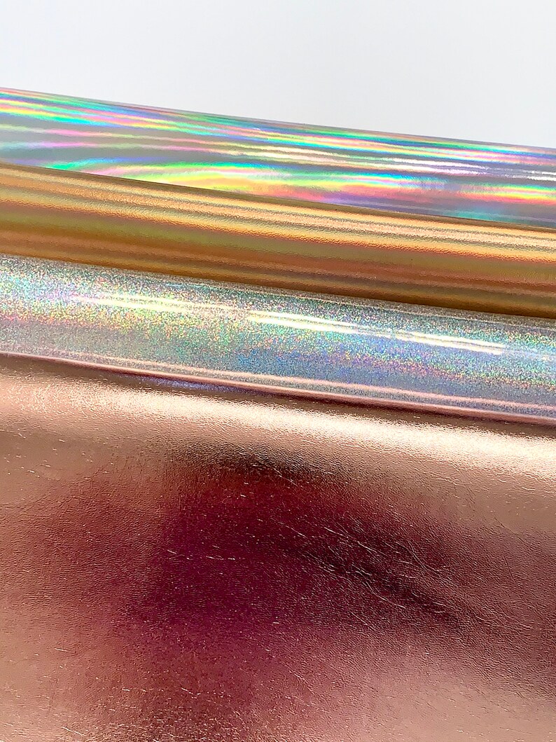 Op de afbeelding: Drie vellen iriserende holografische vinyl in goud, zilver en roze goud.