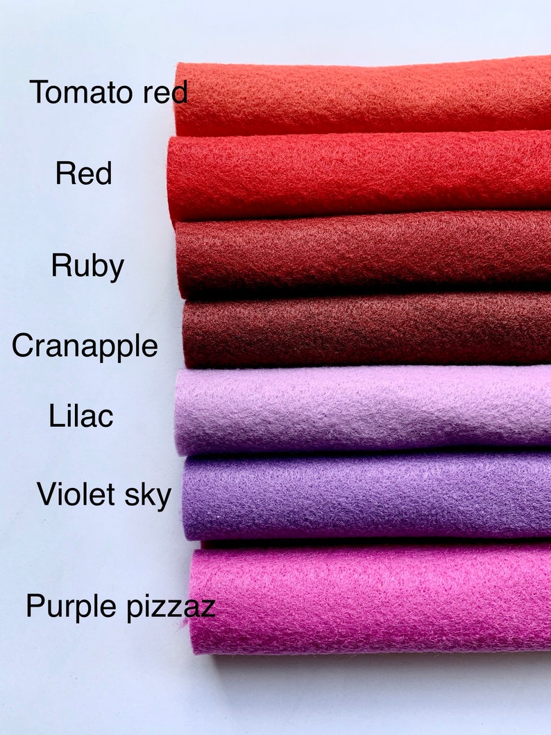 May include: A stack of seven felt fabric strips in various shades of red, purple, and pink. The strips are labeled with the names "Tomato red", "Red", "Ruby", "Cranapple", "Lilac", "Violet sky", and "Purple pizzaz".