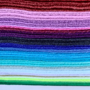 May include: A stack of felt fabric in various colors, including red, purple, blue, green, and light blue. The felt is arranged in a rainbow pattern.