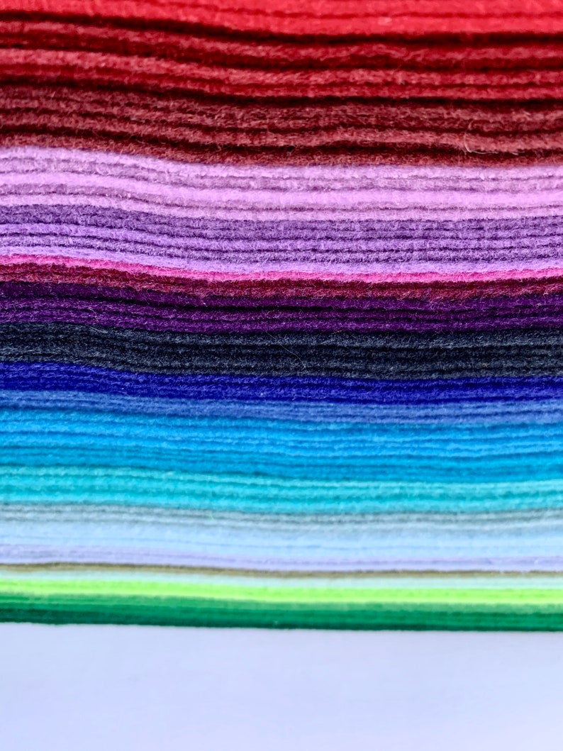 May include: A stack of felt fabric in various colors, including red, purple, blue, green, and light blue. The felt is arranged in a rainbow pattern.