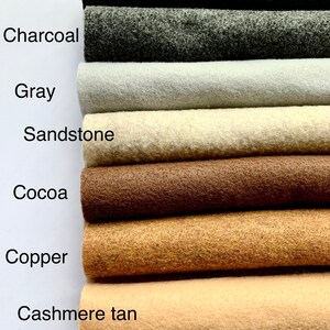 May include: A close-up of eight different colors of felt fabric swatches. The colors are black, charcoal, gray, sandstone, cocoa, copper, cashmere tan, and white.