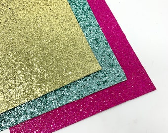 May include: Three sheets of glitter paper in gold, teal, and pink.