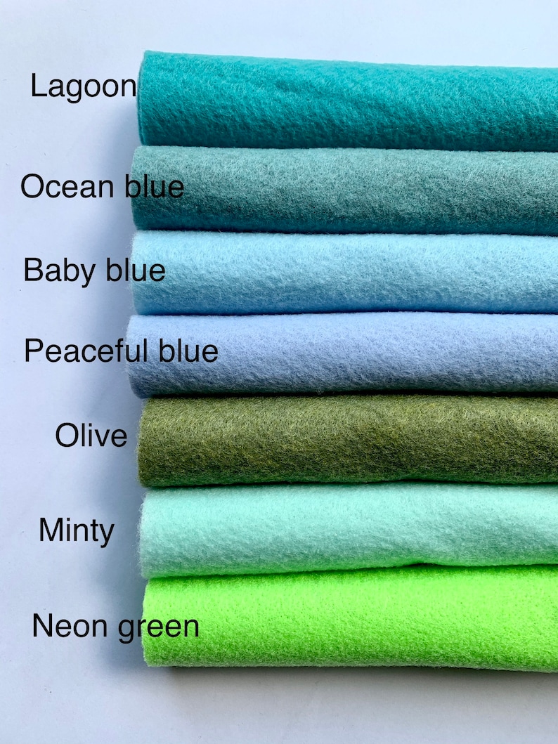 May include: A stack of seven felt fabric swatches in various shades of blue, green, and olive. The swatches are labeled with the following names: Lagoon, Ocean blue, Baby blue, Peaceful blue, Olive, Minty, and Neon green.
