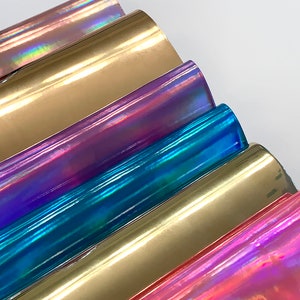 Op de afbeelding: Een stapel van zes iriserende vinylvellen in verschillende kleuren, waaronder goud, paars, blauw en roze.